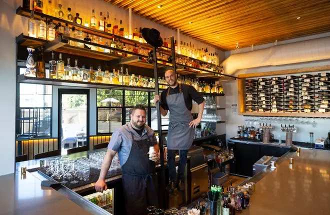 two bartenders photographed inside of a bar