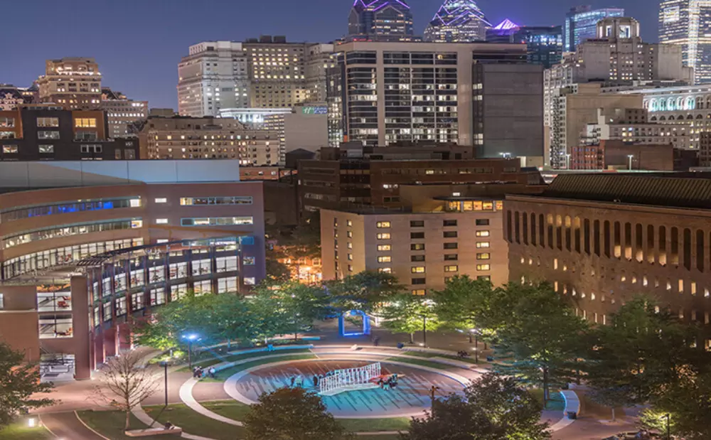 a part of town with a fountain and buildings photographed at night