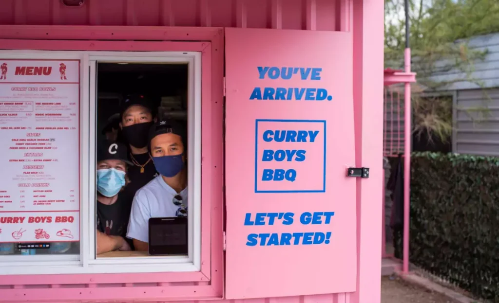 Curry Boys BBQ pink object with workers looking out of the order window