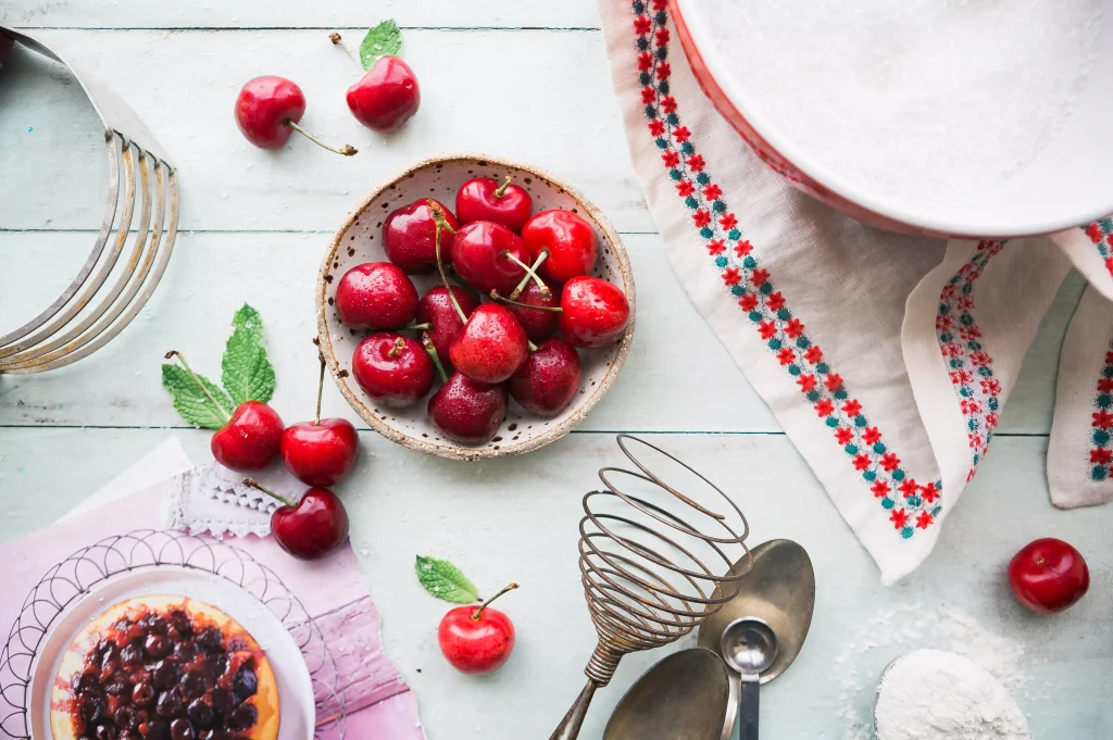 Numerous cherries in a bowl on a table with a colorful table cloth