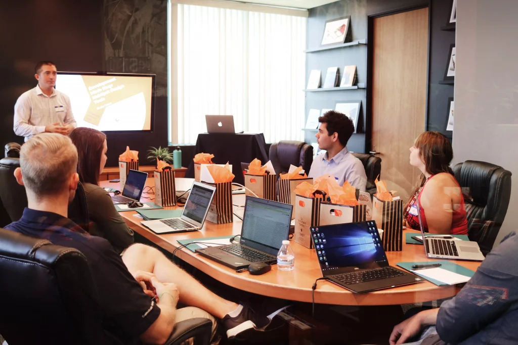 A guy is presenting something to a group of people with laptops