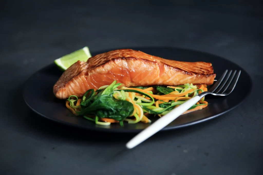 Fish, Salmon in a plate with salad and a fork next to it