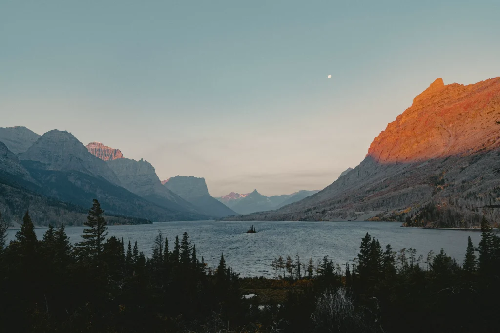 A lake behind trees and mountains