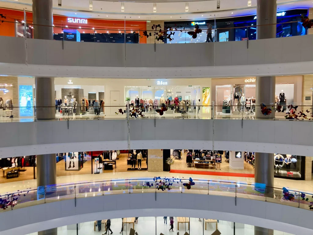 Shops in a shopping center with people buzzing infront of them