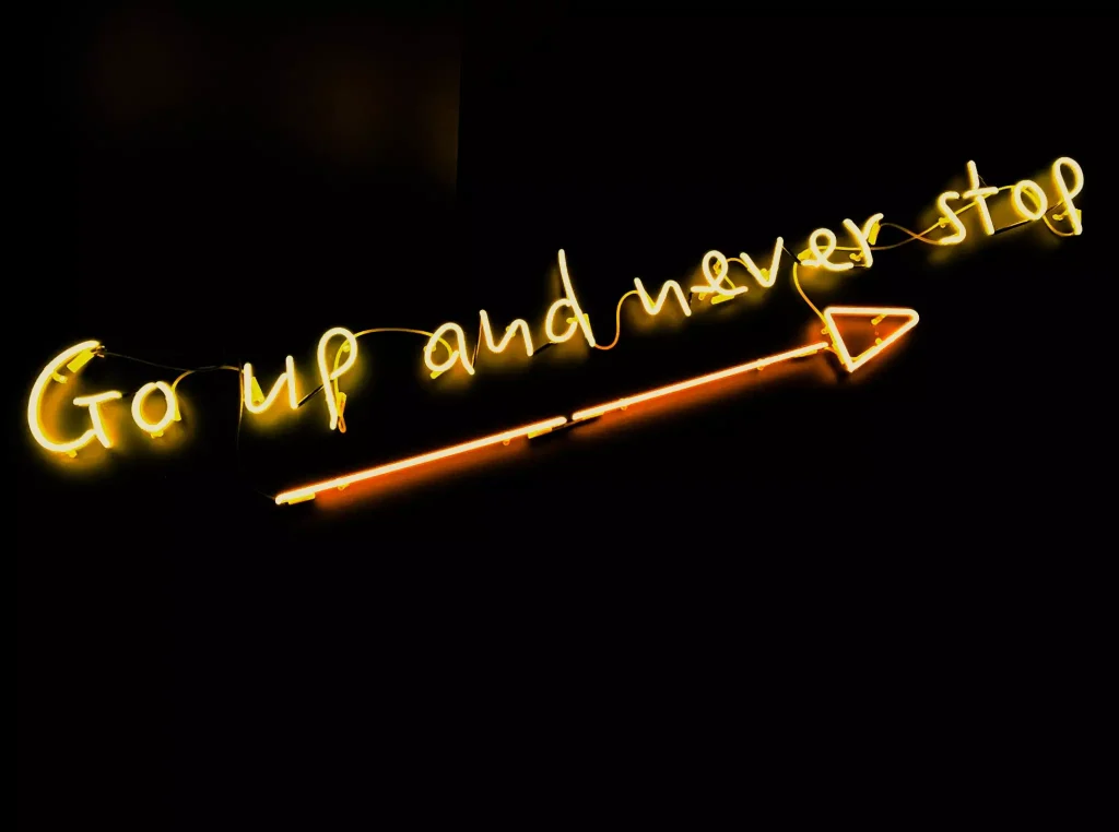 An arrow below a sign that says go up and never stop