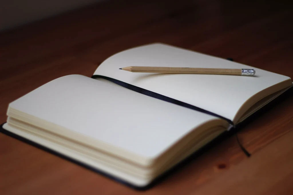 An empty notebook with a pencil on top