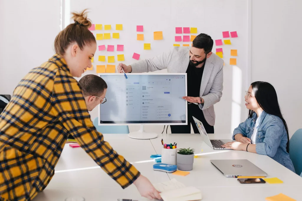 A guy is presenting something to a group of people on a monitor