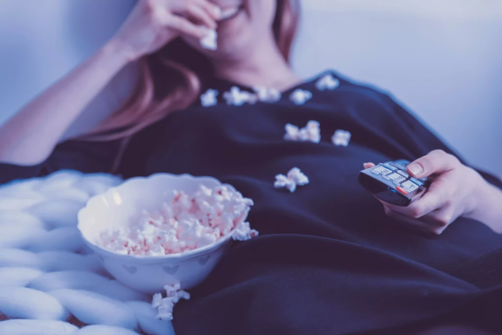 A girl eating popcorn and enjoying a movie