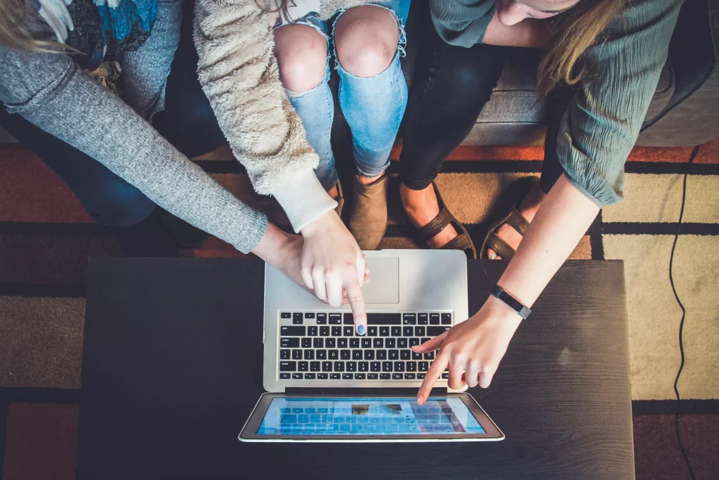 Three persons pointing at a laptop