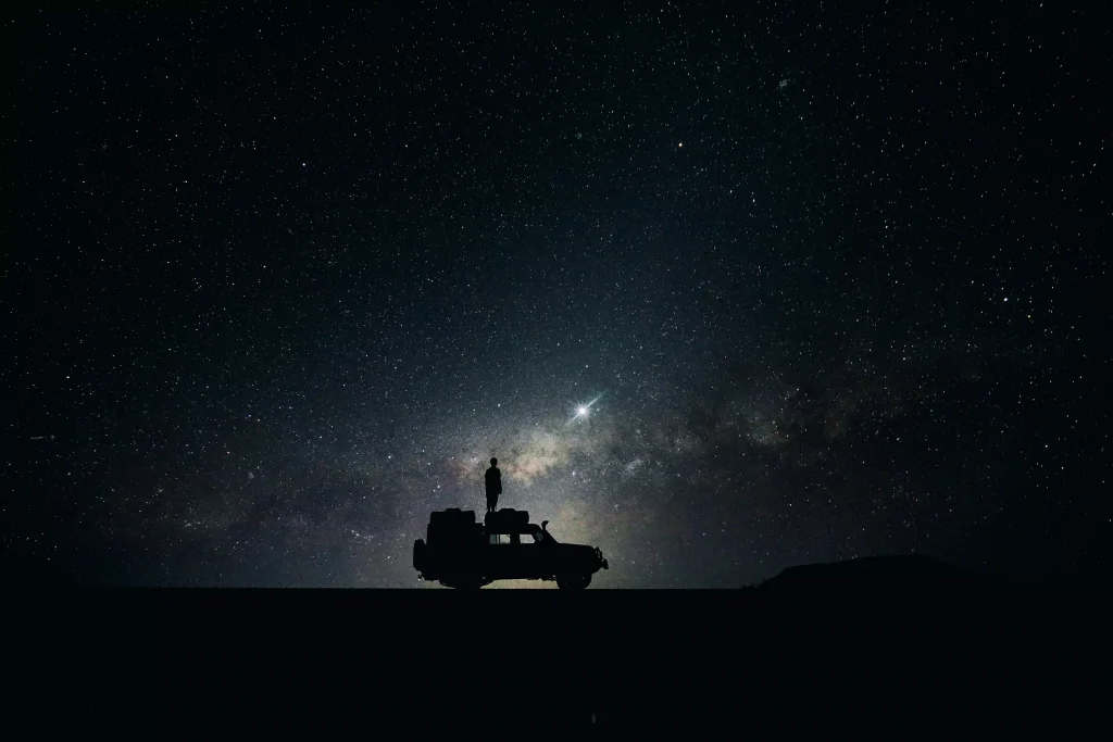 A distant car photographed at a clear night full of stars