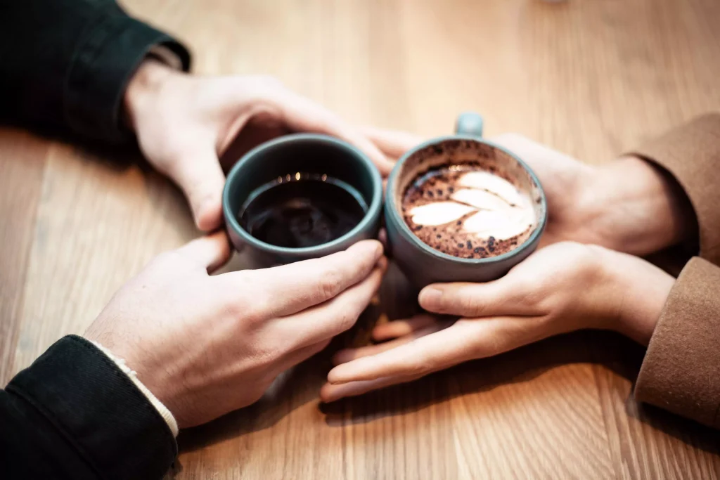 Two coffe cups wrapped with two hands