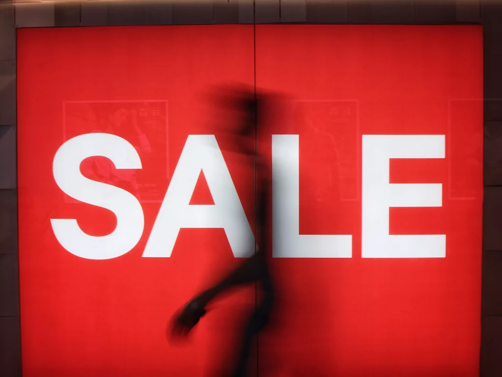 A sign that says sale with a shadow of a man