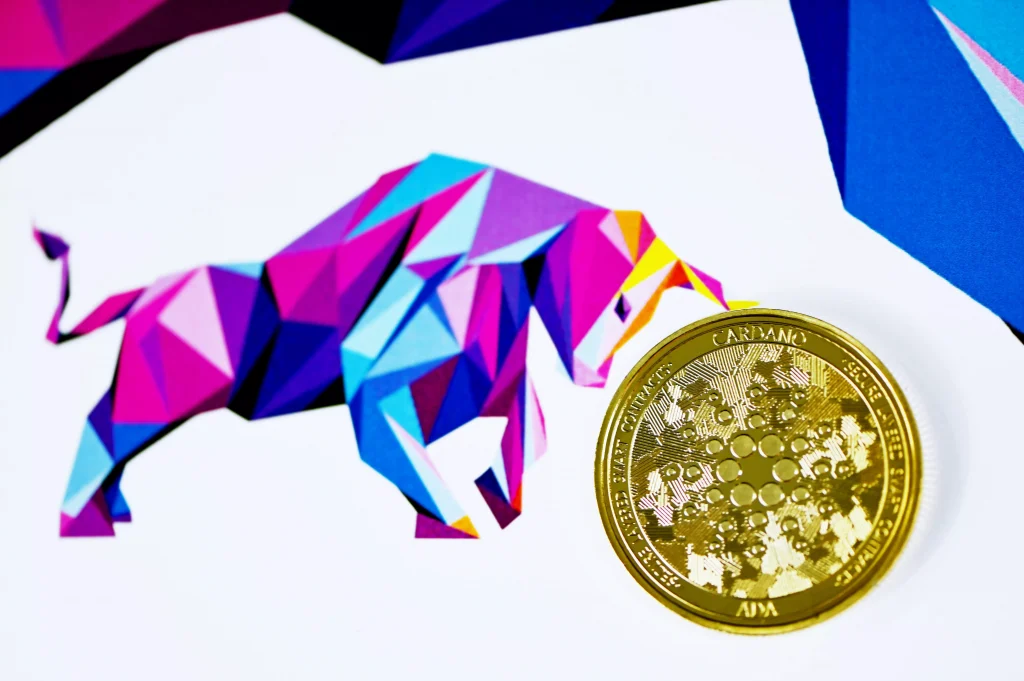 A caricature of a bull next to a real Cardano cryptocurrency gold coin