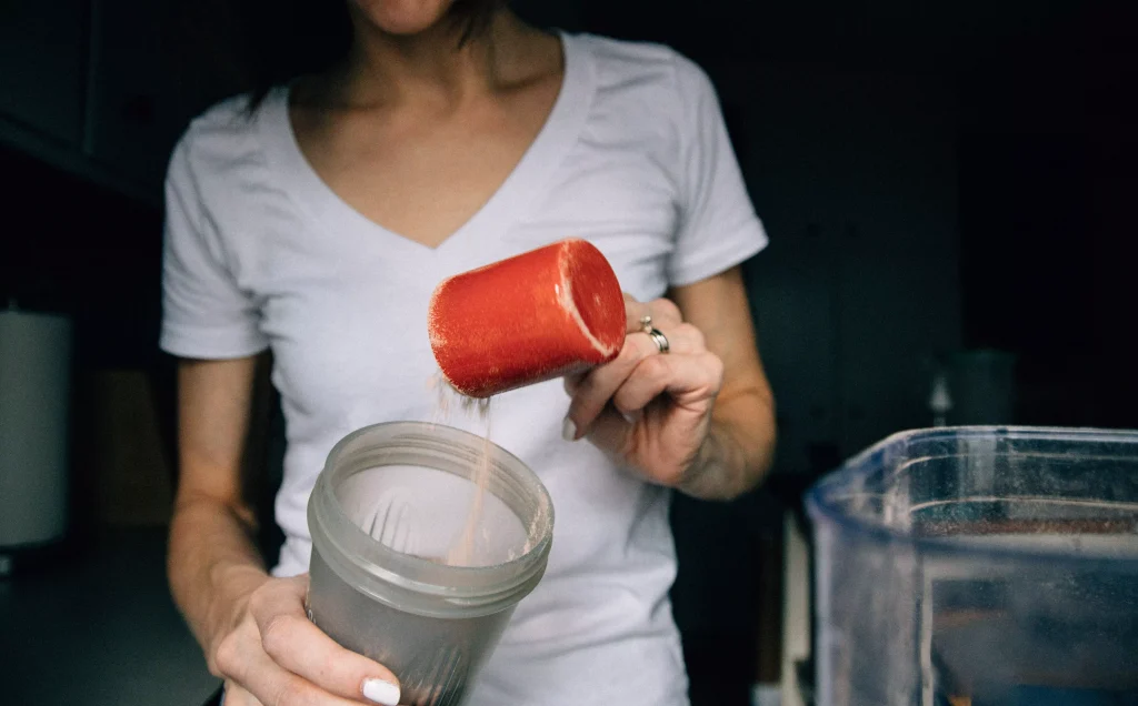 Fit Women preparing shake with proetin powder in a blender