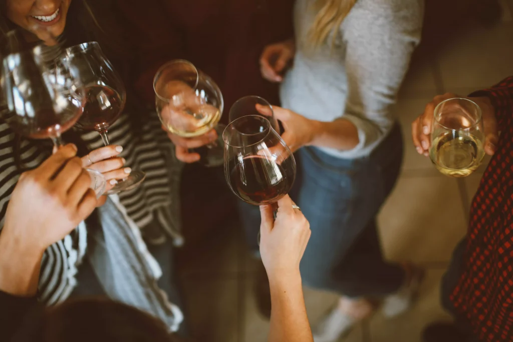 A group of people at a bar holidng their glass up to a cheers