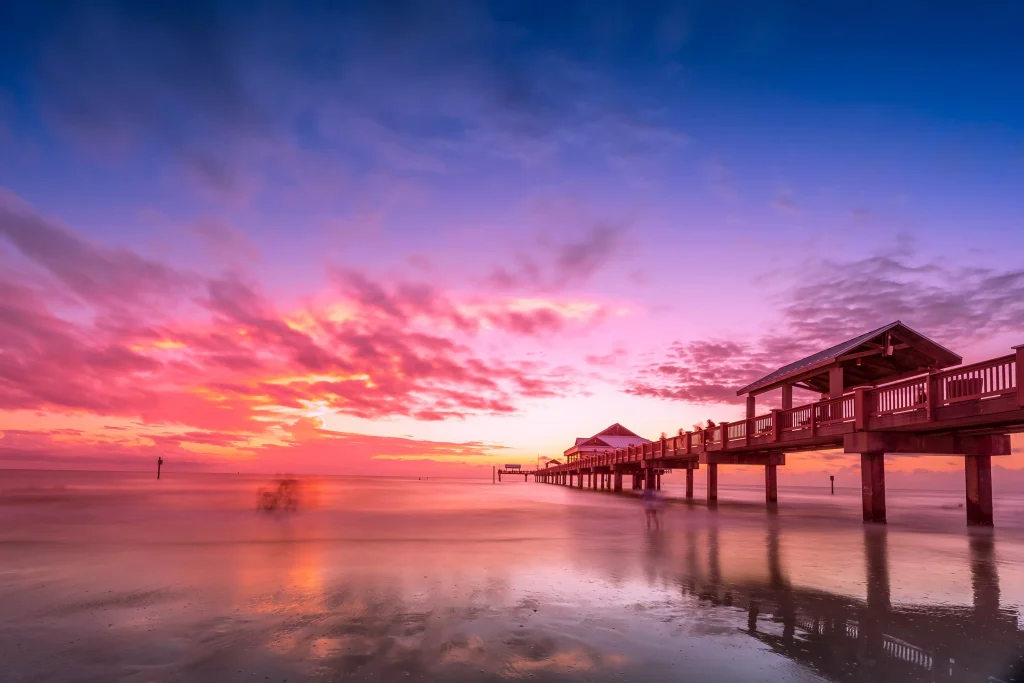 Sunset with pink colors on sky on a beach with a dock