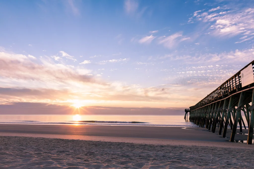 Beautiful sun on the beach next to a pier