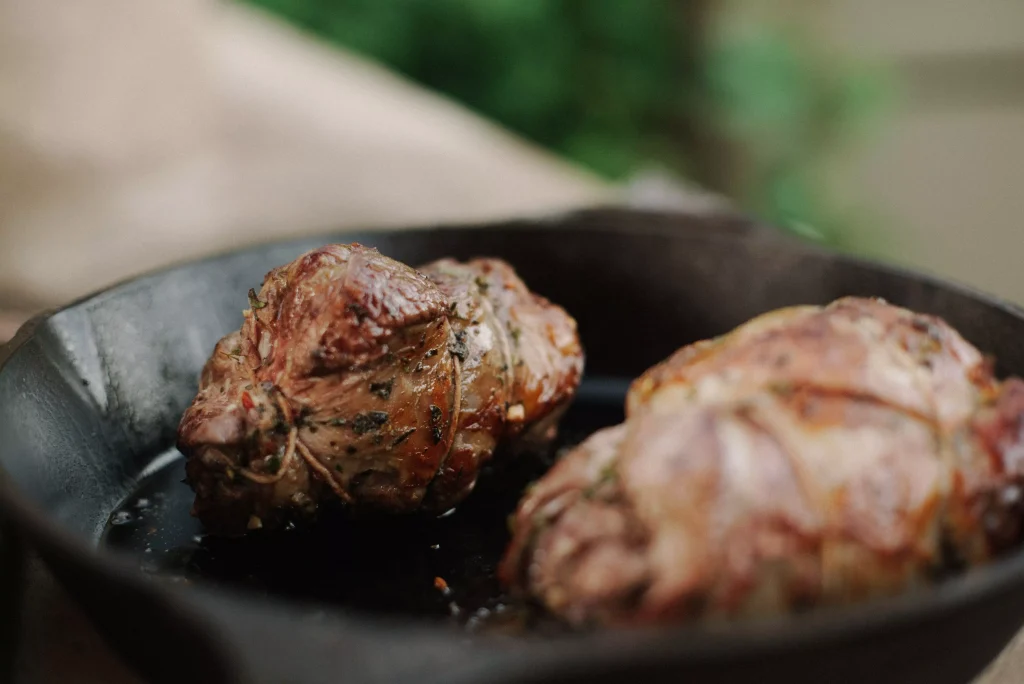 Meat being cooked in pan, seasoned and delicious.