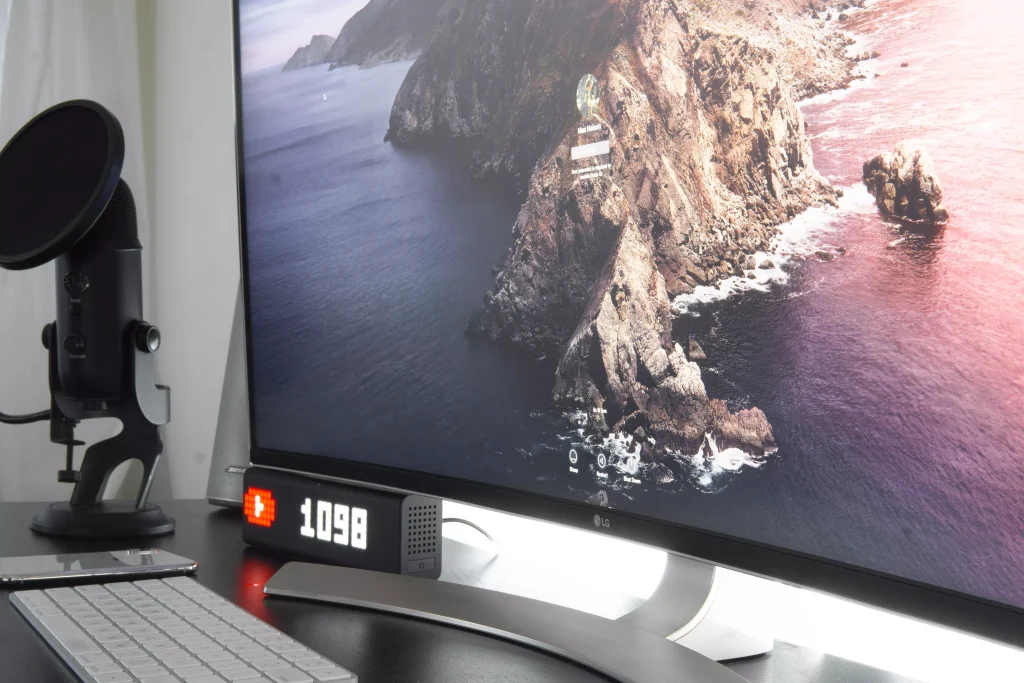 Desk setup with big monitor and a keyboard and michrophone