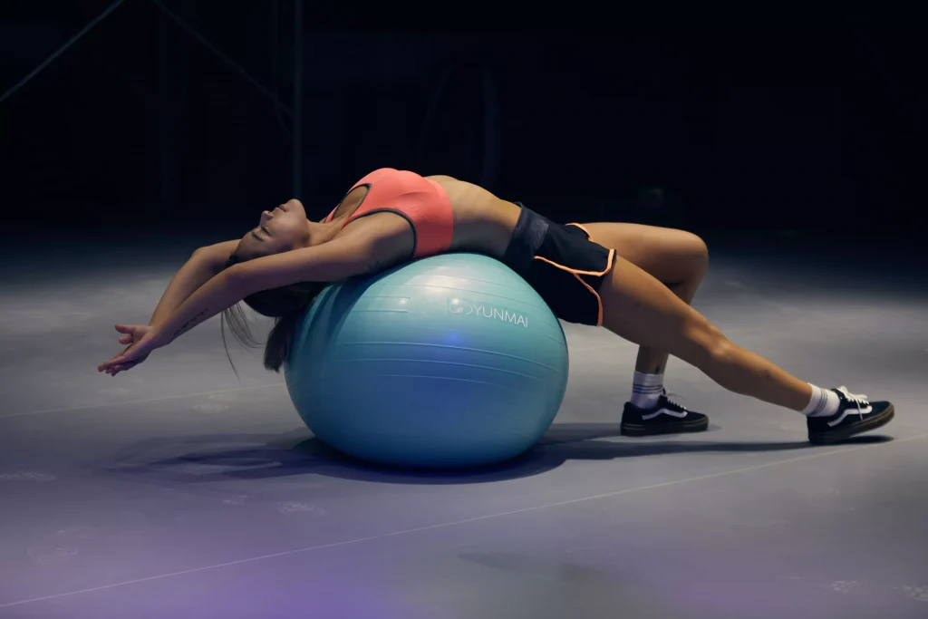 A women in training clothes stretching on a yoga ball