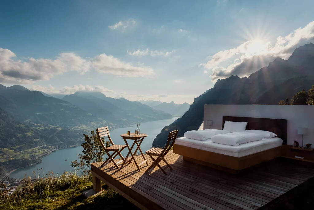 A hotel room with a view over a river and with a bed outside in the sun