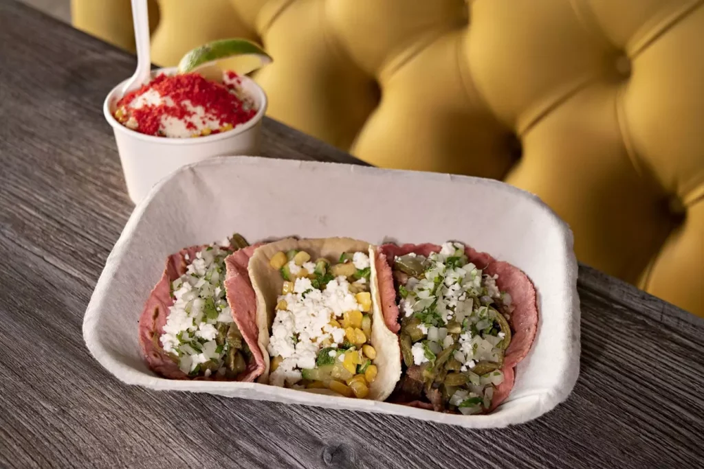 tacos in a white cardboard box on a table next to a yellow couch