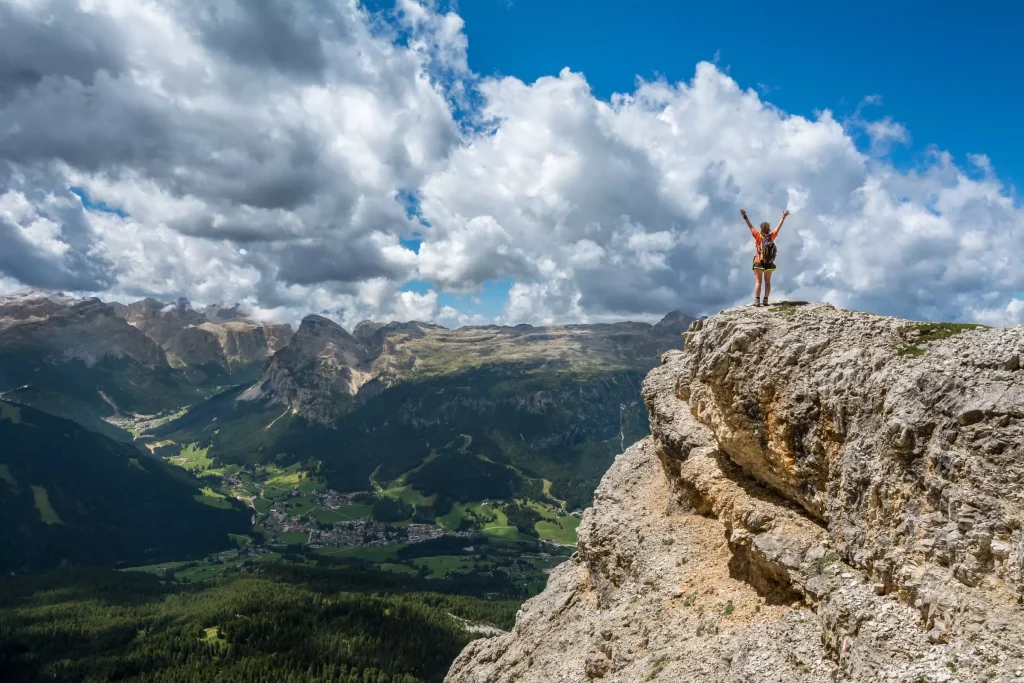 Women on a hill cliff with risen hands, overlooking the beautiful nature