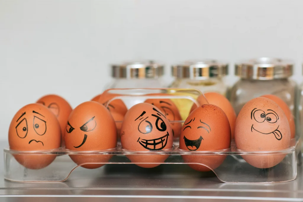 Eggs in the fridge, with funny facial expression drawn on them