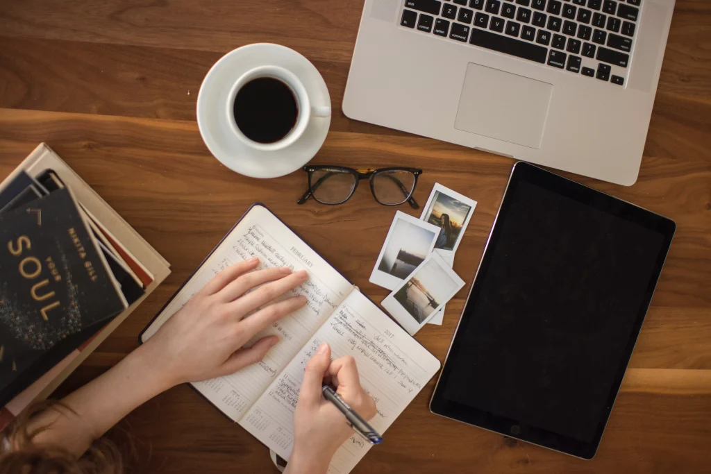 A freelance writer preparing for writing, on his table there are his galssess a few pictures and a filled up coffe cup