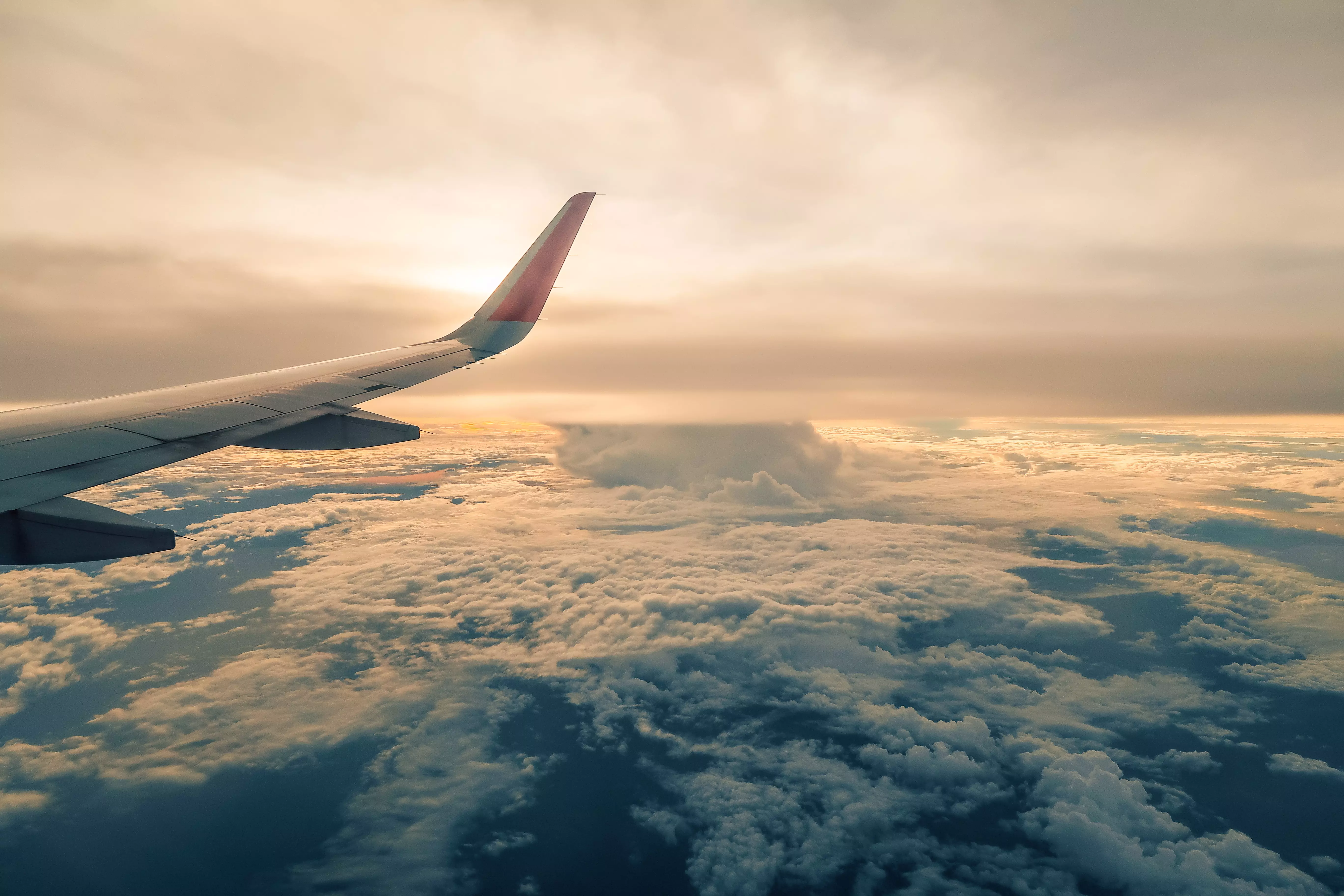 Airplane wing, photographed from inside the airplane, in the clouds, on a sunny day