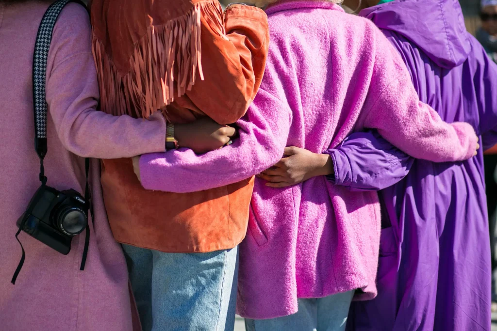 Four people with pink orange pink violet coats respectively huging