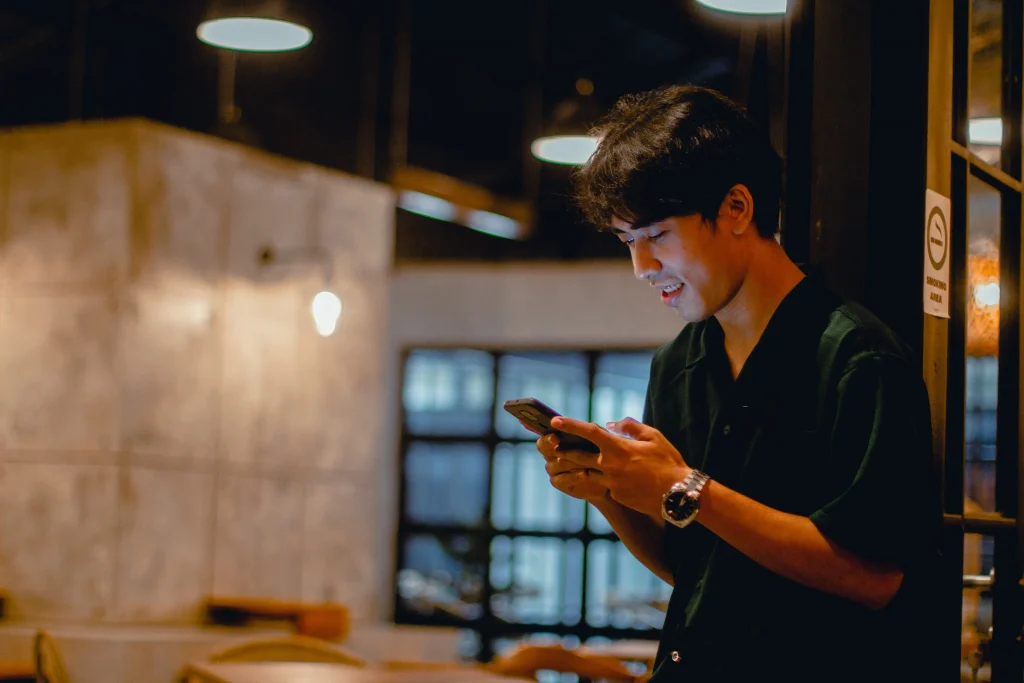 A man texting someone, and laughing at the same time