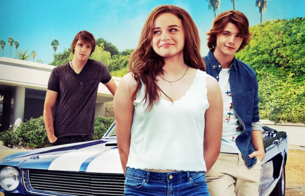 two guys and a girl standing next to a car