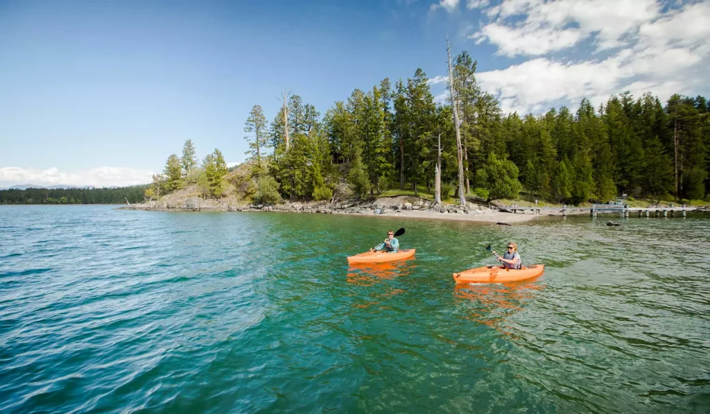 two people in little orange boats on a lake