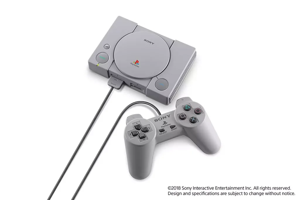 a gaming console with a controller next to it in the color of grey