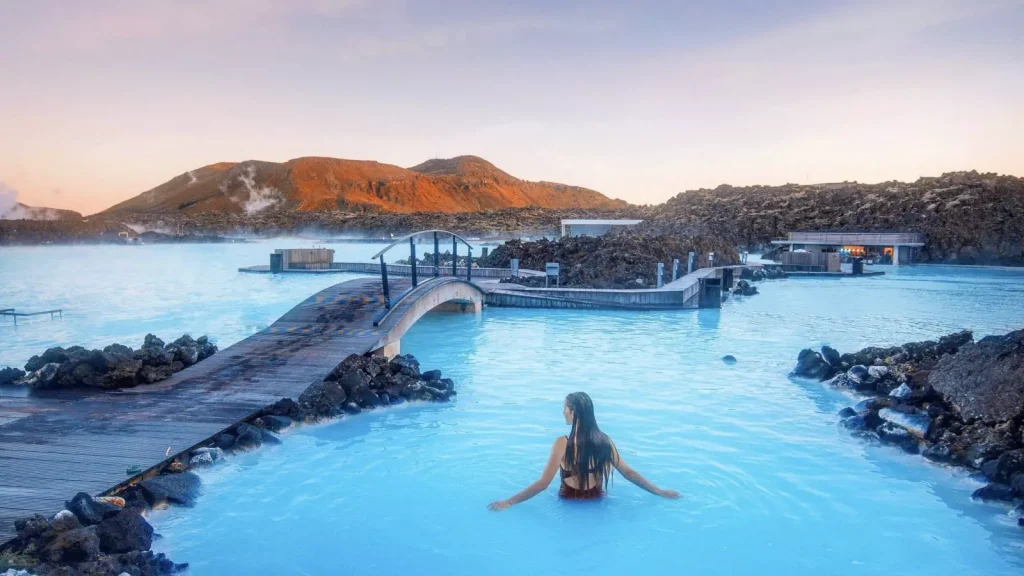 a girl relaxing in a blue pool next to a wooden bridge