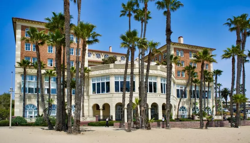 a white villa house behind some palms on a beach