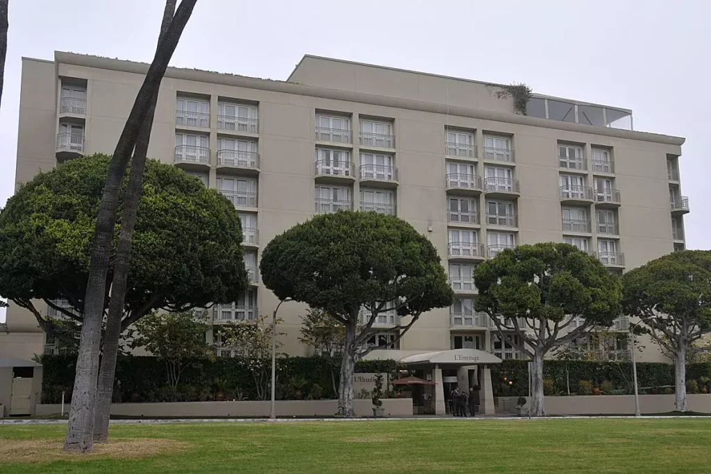 a school with a lot of windows behind green tall trees