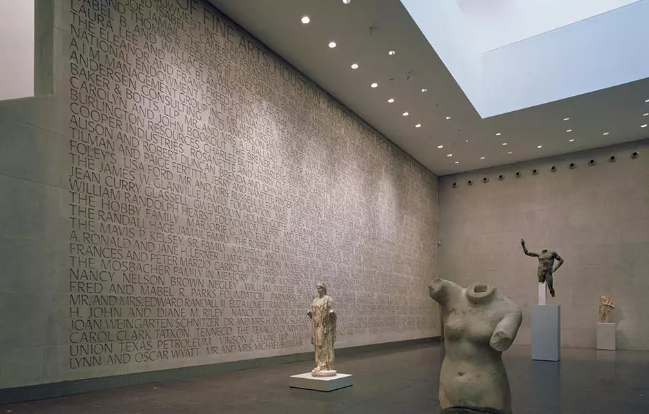 art statues inside of a building with grey walls