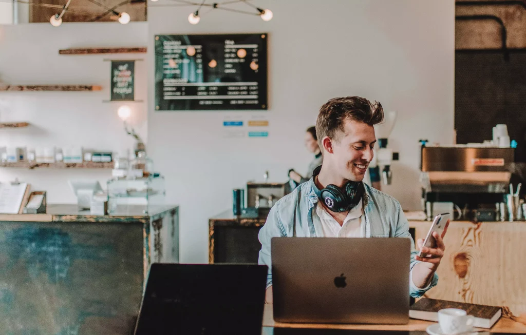 a guy with headphones looking at his phone and smiling