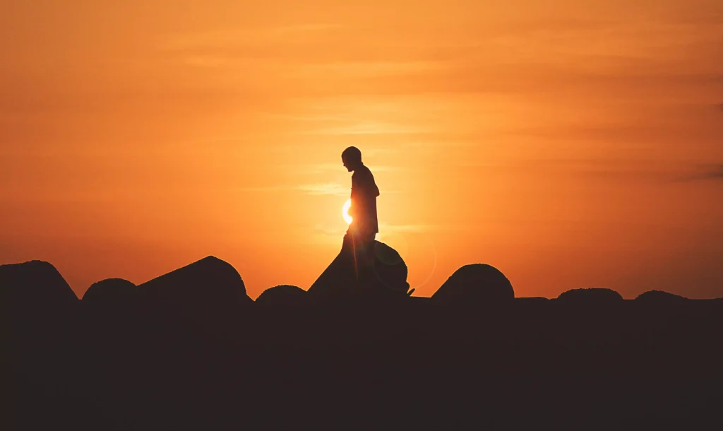 man standing on a hill in a sunset