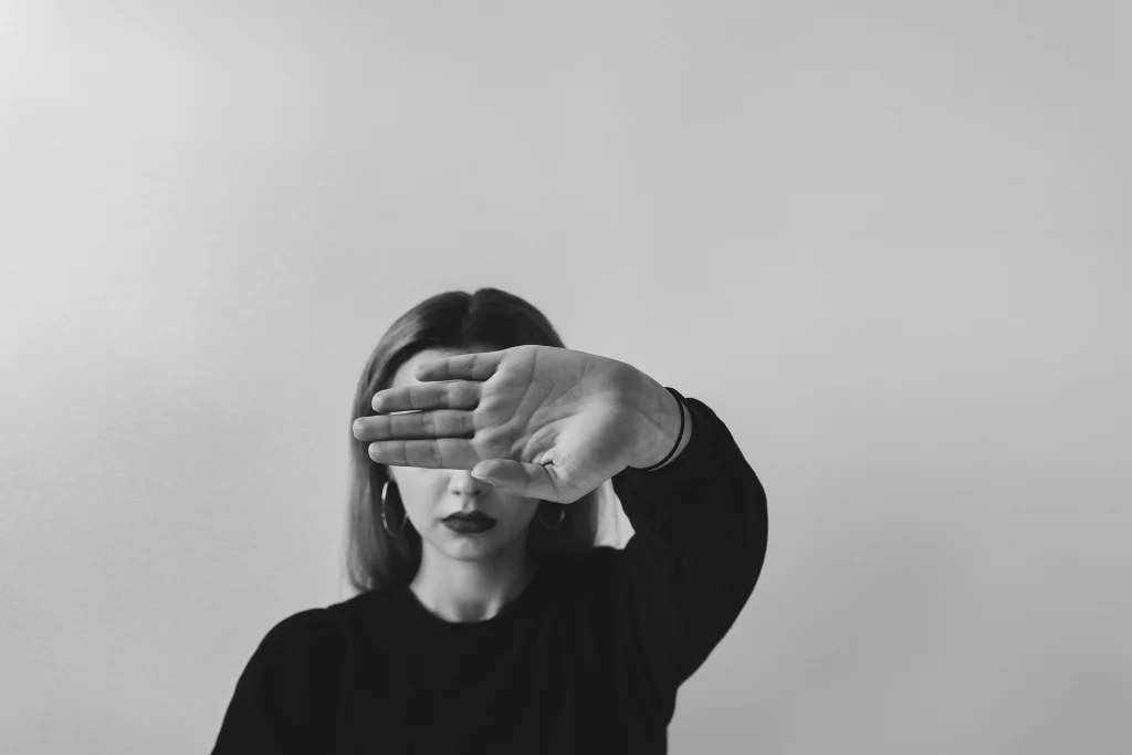 girl in black top covering her face with her hand