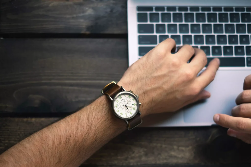 a man with a watch working on his laptop