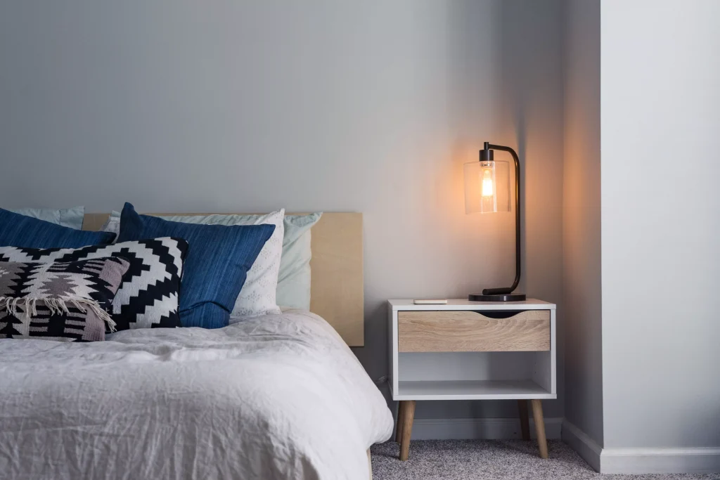 a bed with blue pillows and a book light next to it