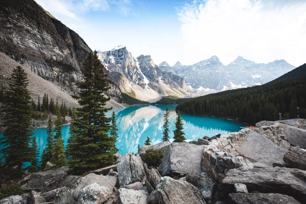 sky blue lake surrounded by mountains and green trees