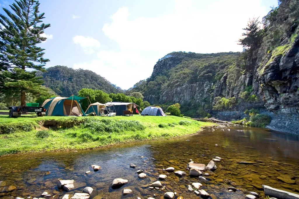 tents ona green field next to a river