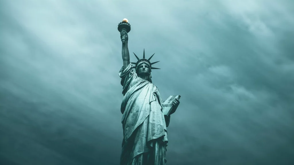 a blue statue holding one hand up photographed on a foggy day