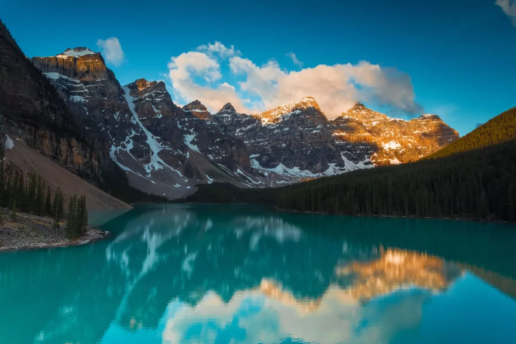 blue lake surrounded by trees and snowy mountains