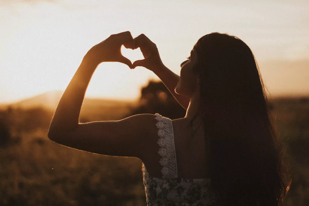 girl making a heart shape with her hands