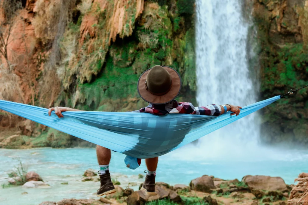 a person with a hat laying infront of a waterfall